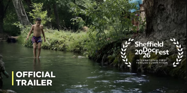 Official trailer image for The Wind’s Thirst, showing a child standing in a river beside the Sheffield DocFest 2026 International First Feature Competition laurel.